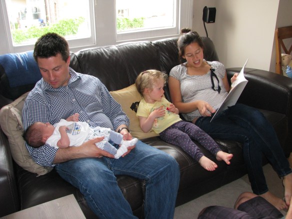 Shoshanna's brother Jonny holding Henry while Helen reads Amaya a story.
